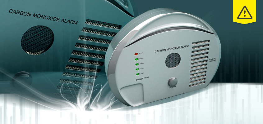 A carbon monoxide alarm with indicator lights is shown prominently, with another similar device in the background. A yellow warning symbol appears in the top right corner, suggesting caution or alert.